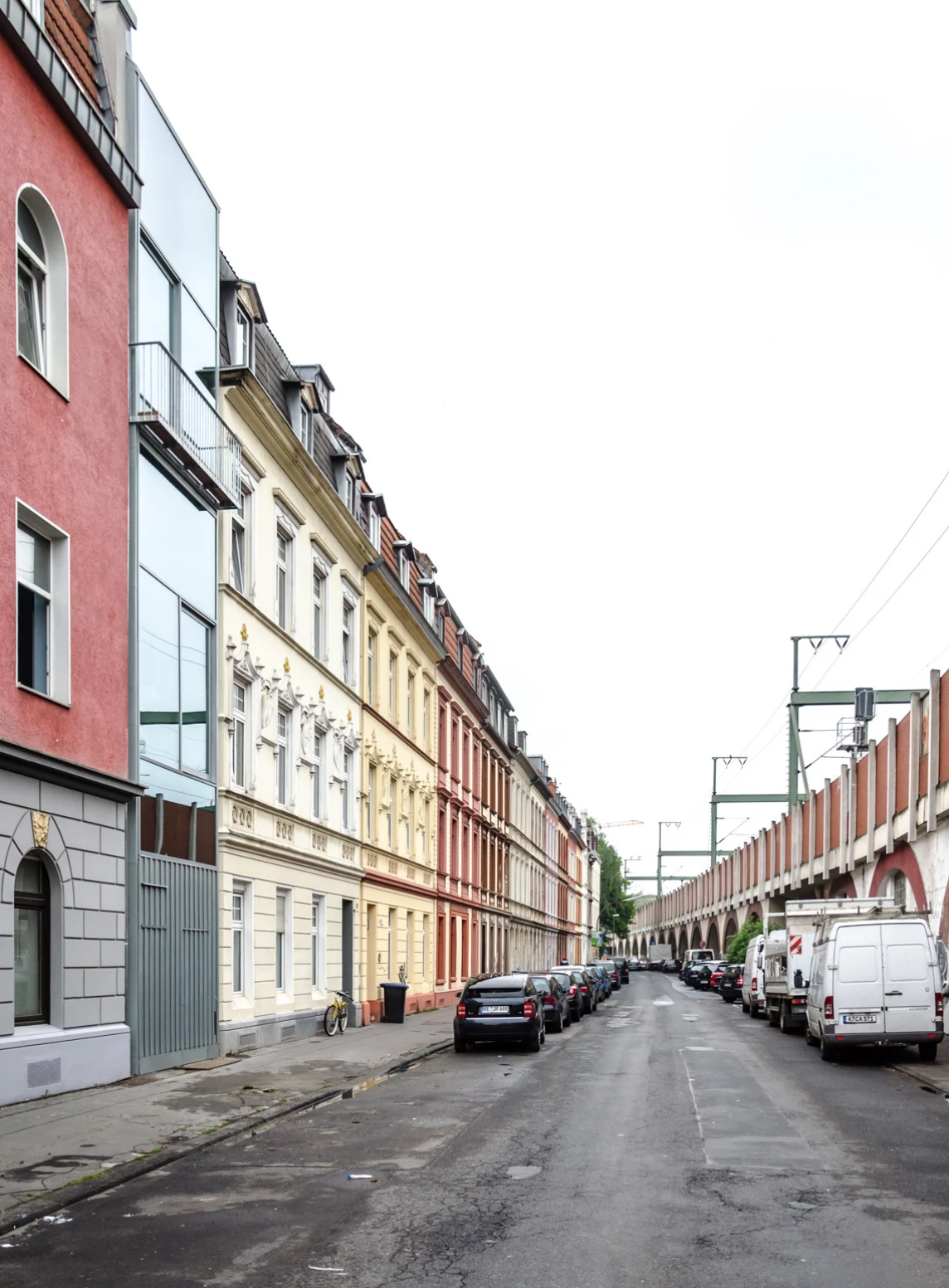 Eine ruhige Straße mit bunten Gebäuden und geparkten Autos, die eine sich wiederholende Architektur zeigt.
